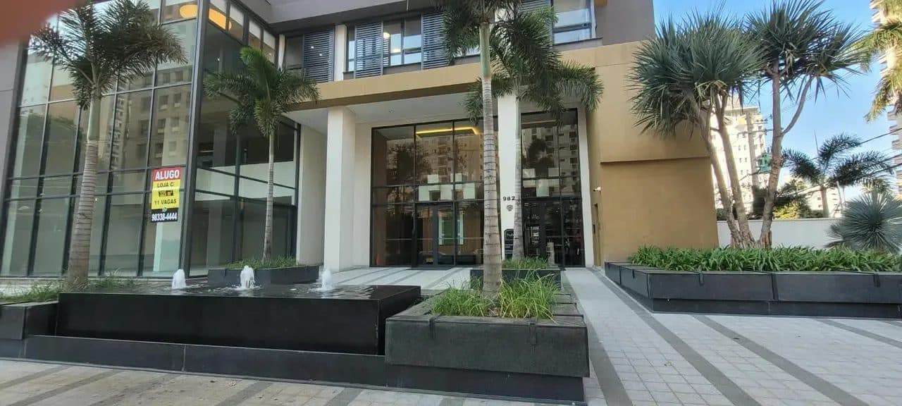 Fachada do edifício com entrada frontal, paisagismo, pilares e espelho d'água