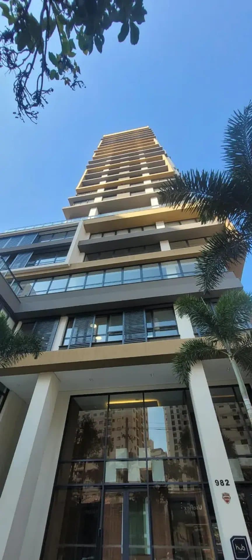 Vista externa da fachada do prédio com varandas e grandes janelas de vidro
