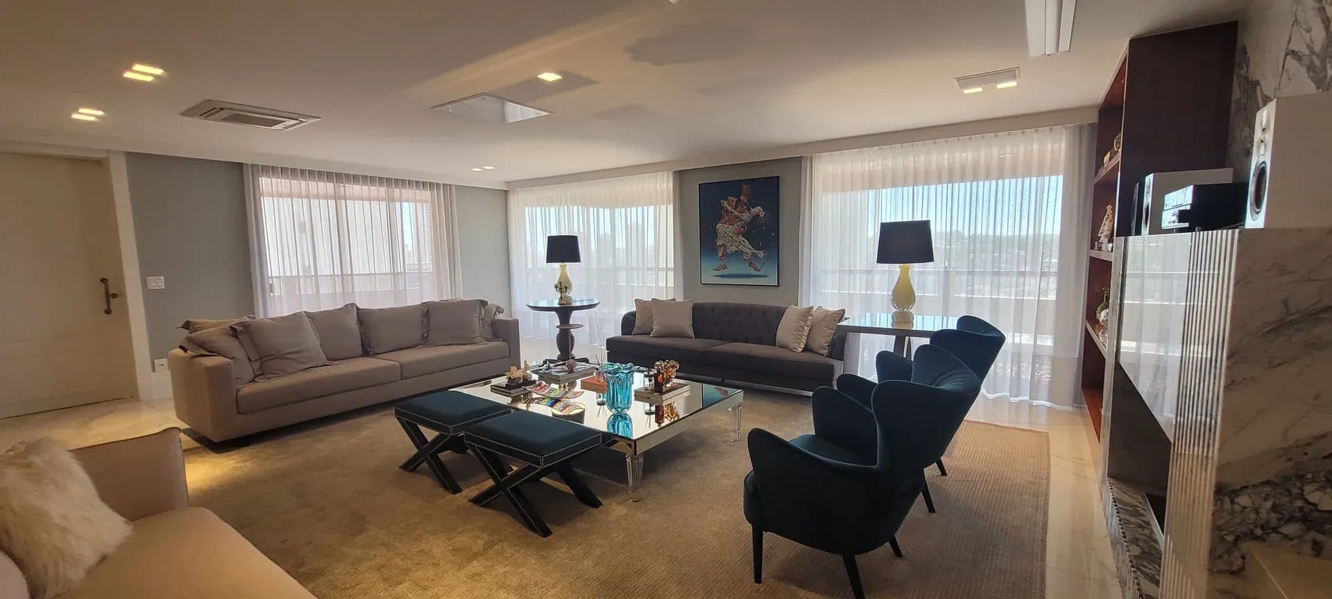 Sala de estar organizada com poltronas escuras e mesa de centro espelhada