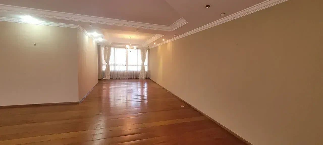 Sala ampla com piso em madeira e iluminação embutida no teto.